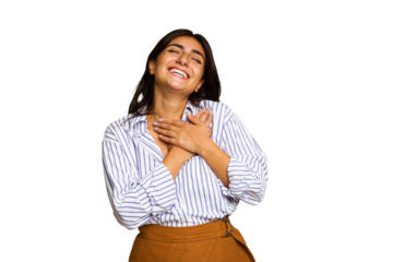 Young Indian woman isolated on green chroma background laughing keeping hands on heart, concept of happiness.