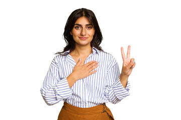 Young Indian woman isolated on green chroma background taking an oath, putting hand on chest.