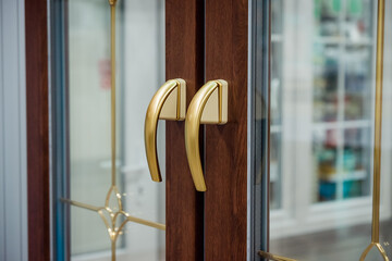 Two golden handles on wooden doors with glass. Interior doors with metal knobs and windows.