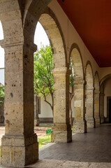 colonial architecture, arches surrounded by vegetation, play of light and shadows inside the space, natural materials