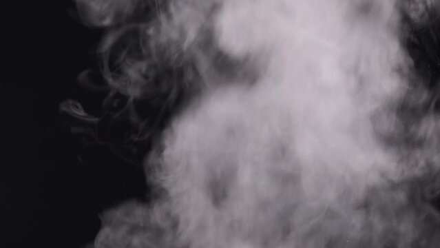 White smoke on black background. A cloud of vapor steam rises up. Floating fog. Explosion steam of vapor. Transparent smoke clouds, abstract fog, steam texture. Real atmospheric effect. 4K.