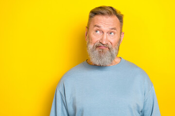 Obraz premium Photo of suspicious funny man pensioner dressed blue pullover looking empty space isolated yellow color background