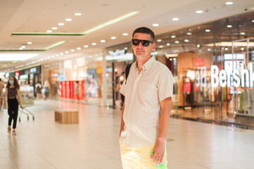 young man in light clothes and sunglasses in the mall. hypermarket navigation concept