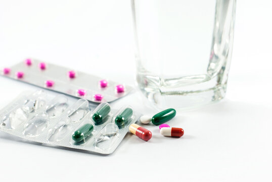 Pills and glass of water on white background. Medicine concept. Selective focus.