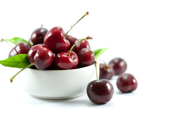 Cherries are placed in a white ceramic cup. and put on a white background.