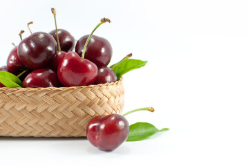 Cherries are placed in a wicker container and put on a white background. Space for text.