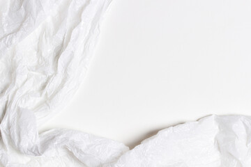 White plastic wrap background. Crumpled wrinkled plastic cellophane on blank white background. Reflecting light and shadow on creases and folds in plastic surface. Texture overlay effect template