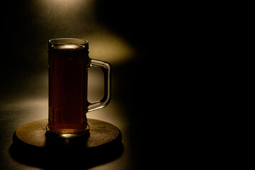 A glass of beer in the backlight , isolated on black smoke background . With space for text  - obrazy, fototapety, plakaty