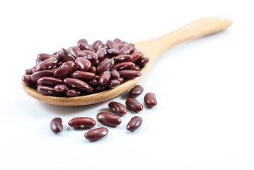 Red beans in a wooden ladle and placed on a white floor, selective focus.