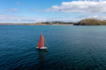 sailboat with red sail on the sea