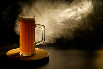 A glass of beer in the backlight , isolated on black smoke background . With space for text 