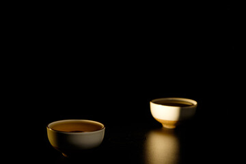 Traditional japanese, chinese asian tea ceremony concept. White ceramic tea cups with lotus on black background. Copy space.
