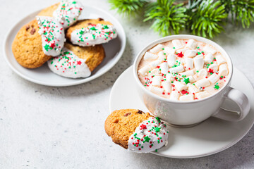 Christmas cup of hot chocolate or cocoa with marshmallows and colored sprinkling and glazed cookies.
