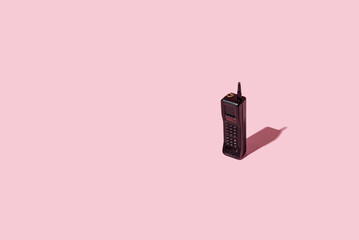 Cordless phone. A symbol of the eighties of the last century. On a pastel pink background. Creative...