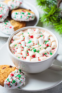 Christmas cup of hot chocolate or cocoa with marshmallows and colored sprinkling and glazed cookies.