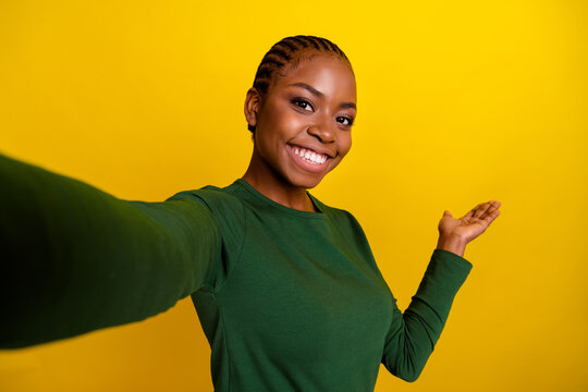 Photo of charming cute young woman wear green shirt recording self video inviting arm come isolated yellow color background