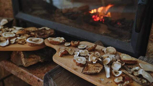 Sliced Mushrooms Drying on Wooden Board by Warm Fireplace with Burning Wood 