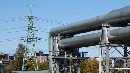 pipeline and power lines, in the photo pipelines and power line support on the background of the blue sky of the buildings of the city