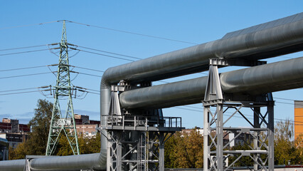 pipeline and power lines, in the photo pipelines and power line support on the background of the blue sky of the buildings of the city