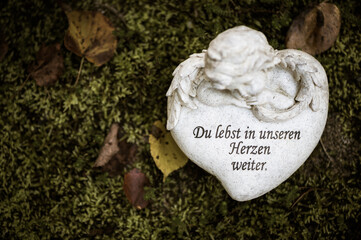 Herz auf Grab mit Schrift "Du lebst in unseren Herzen weiter"