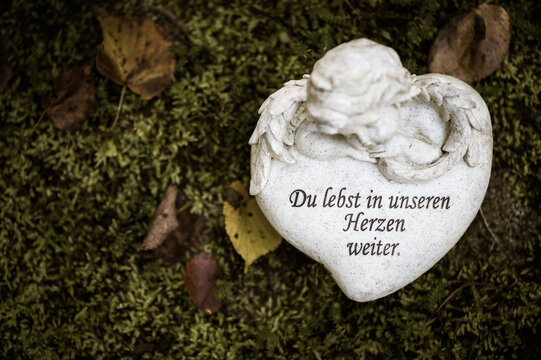 Herz auf Grab mit Schrift "Du lebst in unseren Herzen weiter"