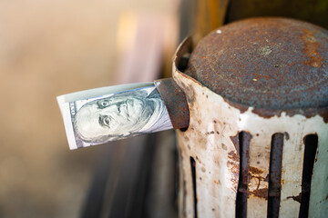 A hundred dollar bill rolled into a tube sticks out of the exhaust pipe of a tractor close-up on a...