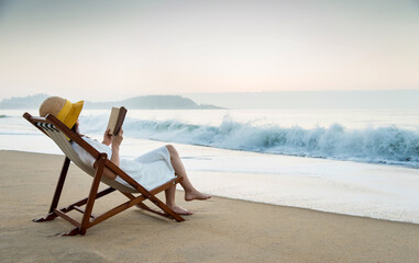 Young lady reading a book on the beach.