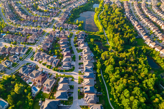 Aerial View Of Luxury Wealthy Style And Clean Single Family Homes In America With Parking Space For Cars And Large Green Backyards. Golden Hour Evening And Houses In Very Geometrical Setting Pattern.