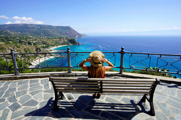 Traveling in Italy. Panoramic view of fashion girl sitting on bench in Capo Vaticano viewpoint on the Coast of the Gods, Calabria, Italy.
