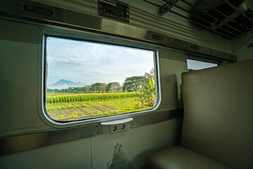 Riding a train in Indonesia sitting by the window watching the tracks and the view outside the window of the train speeding towards its destination