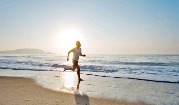Young man running along beach  in the morning