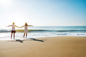 Young couple embracing enjoying ocean on beach.