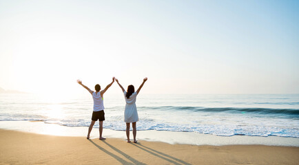 Young couple embracing enjoying ocean on beach.