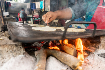 Closeup to the stove with a metal plate in which tortillas are being cooked