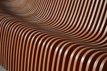 Wooden bench element, brown slats with a rounded edge. Abstract background.