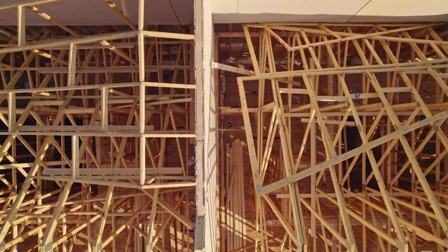  Modern North American home in construction. Aerial view of unfinished city house with wooden roof ribs frame structure. Roof beams under construction.