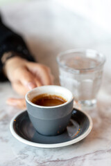 Fototapeta premium Female hand holding cup of espresso. Morning ritual at the cafe.