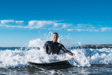 Surfer man smiling in the sea while the force of the sea breaks his back