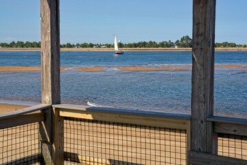 Sailboat tacking across Newburyport harbor channel viewed from boardwalk