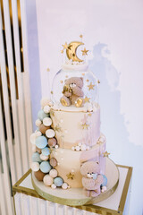 Tiered cake decorated blue, gold, and brown decor. Baby shower. Trendy Cake with a figure bear, moon, and stars for a boy or girl. Celebration baptism concept. Delicious reception at a birthday party.
