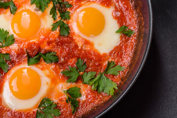 Shakshuka, a dish with fried eggs with tomato sauce, sweet pepper, garlic, onions, spices and herbs