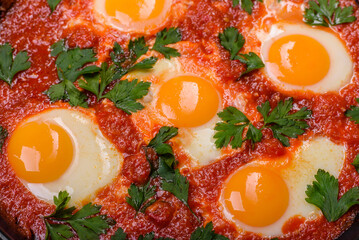 Shakshuka, a dish with fried eggs with tomato sauce, sweet pepper, garlic, onions, spices and herbs