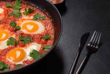 Shakshuka, a dish with fried eggs with tomato sauce, sweet pepper, garlic, onions, spices and herbs