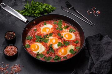 Shakshuka, a dish with fried eggs with tomato sauce, sweet pepper, garlic, onions, spices and herbs