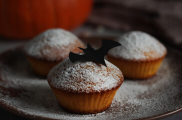 powdered muffins with pumpkin, pumpkin seeds and black bat