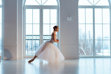ballerina in long white tulle skirt, crouching in bow pose,