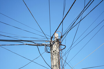 Crossed electric and communication wires in blue sky background. 