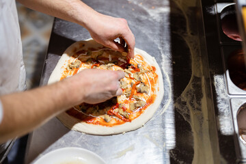 Pizza making process. Male chef hands making authentic pizza in the pizzeria kitchen.