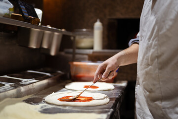Pizza making process. Male chef hands making authentic pizza in the pizzeria kitchen.