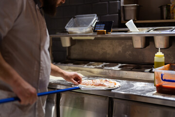 Getting ready to place tasty Italian pizza in the oven. Chef in the restaurant kitchen